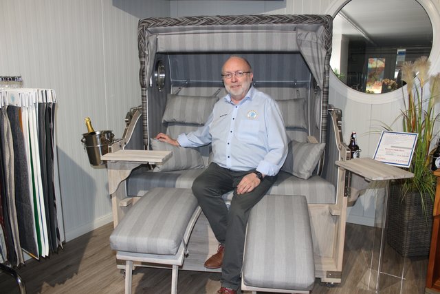 Manfred Gaus, Mitarbeiter der Strandkorb-Manufaktur, wundert es nicht, dass das Modell "Kampen Teak Vintage" derzeit der Bestseller unter den Strandkörben ist. Der geräumige 2,5-Sitzer, der in rund 100 verschiedenen Stoff-Variationen erhältlich ist, erfüllt jeden Wunsch aller Landhausstil-Liebhaber und besticht durch seine einzigartige Optik mit handgebürstetem Teak-Holz. Wenn dann noch kühles Bier und Perlwein in den Getränkehaltern bereit stehen, kann man sich ganz entspannt zurücklehnen.