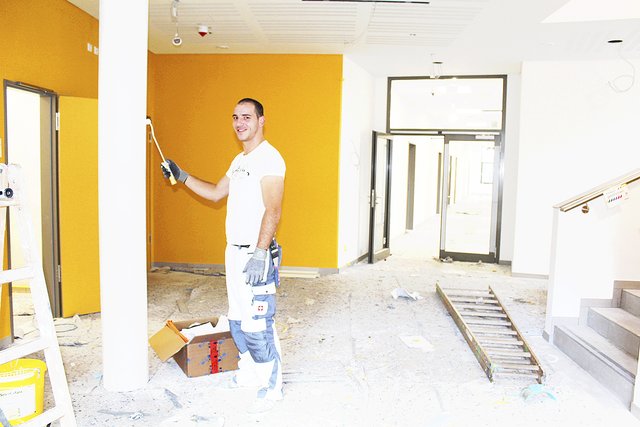 Gelb strahlt den Besuchern des Rathauses in der Eingangshalle entgegen. Maler Matej Ljubas nimmt letzte Ausbesserungen vor