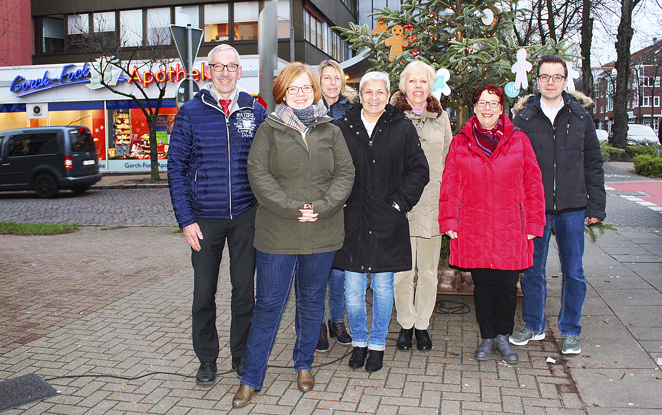 Harald Beckmann (v.li., Marktkauf) Frauke Schulte (Jugendamt), Petra Kersten (IBB), Cordula Hein (et ceTEEra), Mara Mikulis (Gorch-Fock-Apotheke), Beatrice Kietzmann (Sie Dessous) und Tobias Benecke (WOCHENBLATT) vor dem Wunschbaum und dem Schaufenster im Hintergrund, in dem die Geschenke ausgestellt sind
