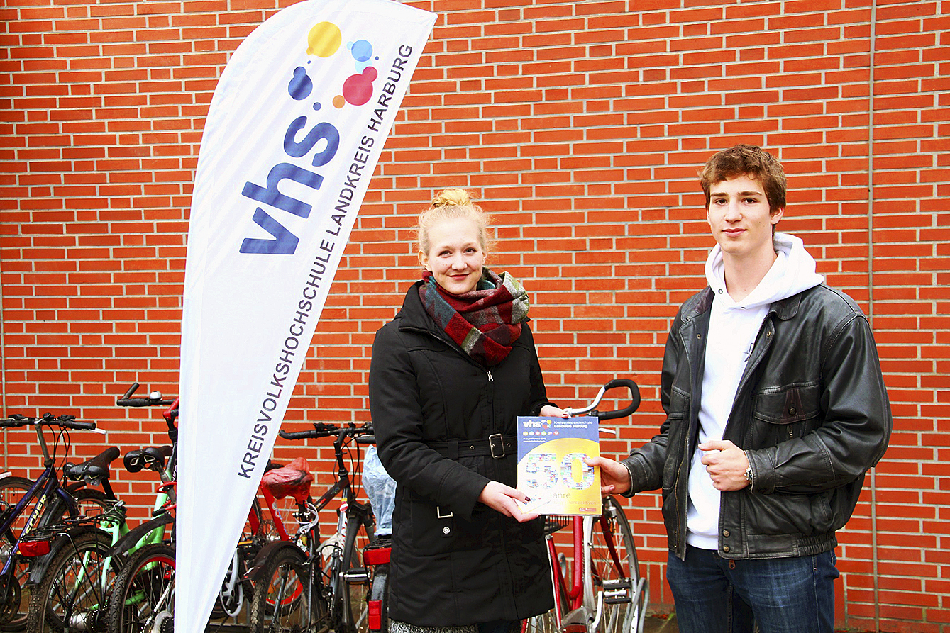 Franziska Wille, KVHS-Mitarbeiterin im Bereich Sprachen und Integration, überreicht ein Programmheft an Elrik Vosberg