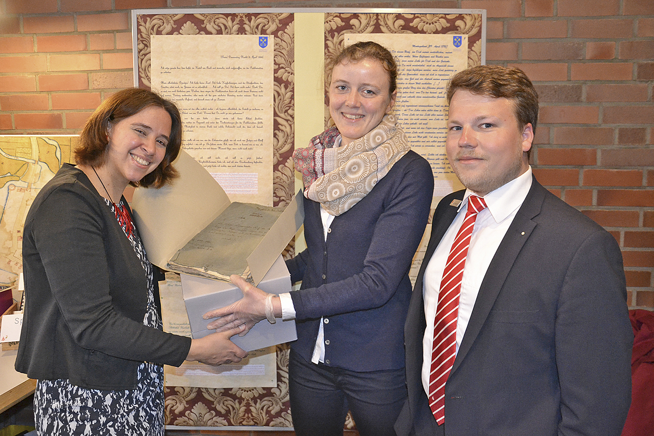 Stadtarchivarin Eva Drechsler (li.) übergibt zusammen mit Matty Neumann von der Sparkasse Harburg-Buxtehude die Hexenakten an Restauratorin Gudrun Kühl