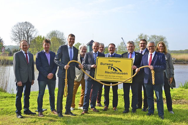 Ein symbolischer Akt: Die Bürgermeister von Hechthausen und Burweg halten das Schild vor der Oste zusammen mit ihren Gästen hoch und zeigen eine Einheit Fotos: sc