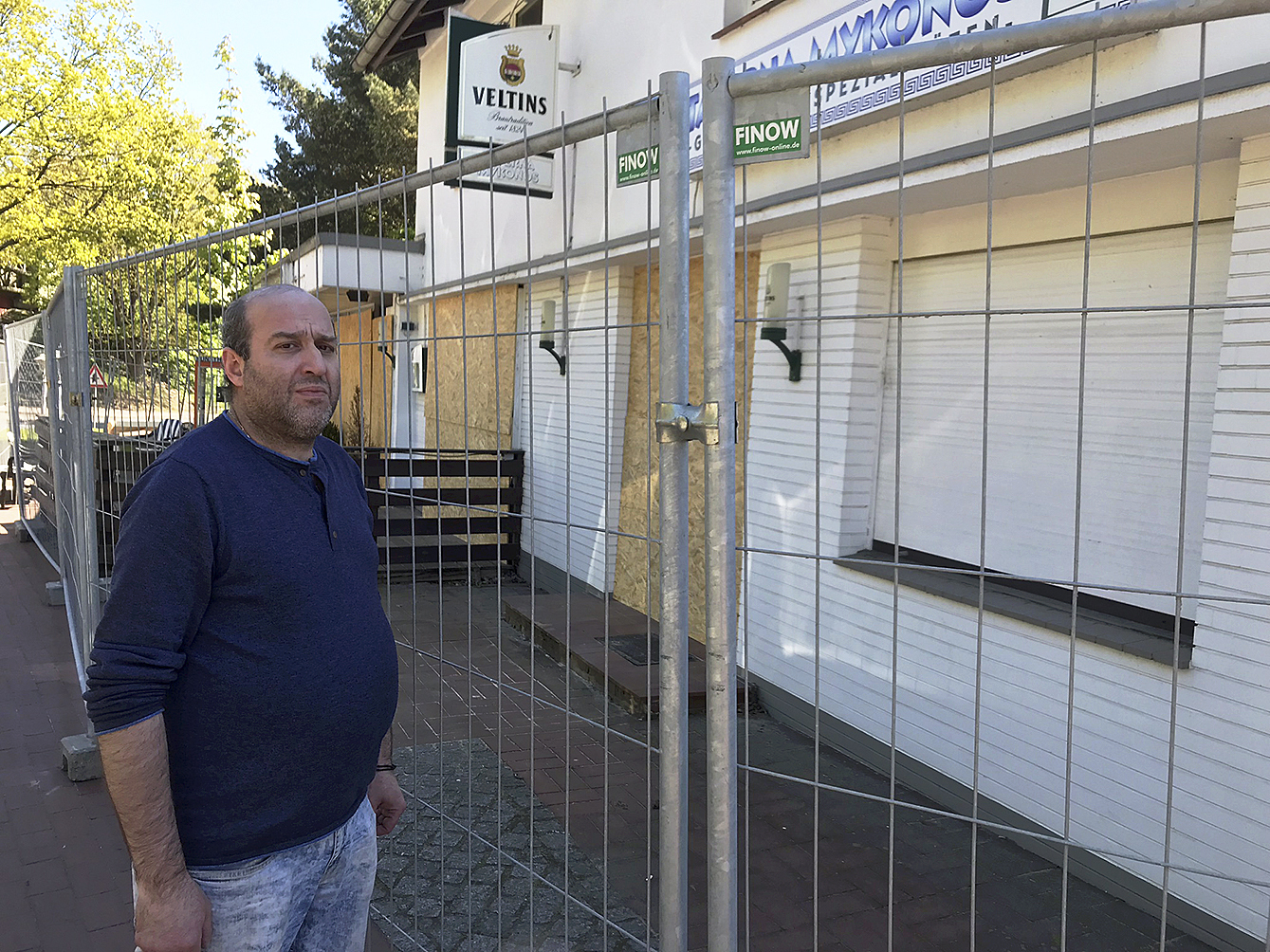 Der Imbiss-Betreiber Vasileios Drosos steht vor seinem Lokal. Mit einem Bauzaun und Holzbrettern wurde das Gebäude für den Abriss vorbereitet