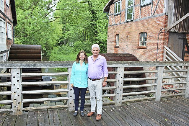 Vor denkmalgeschützter Kulisse: Katja Hüttmann und Ehemann Willi Brink zwischen dem Schrotmühlenbau mit dem zu restaurierenden Wasserrad (re.) und dem Getreidemühlen-Trakt.