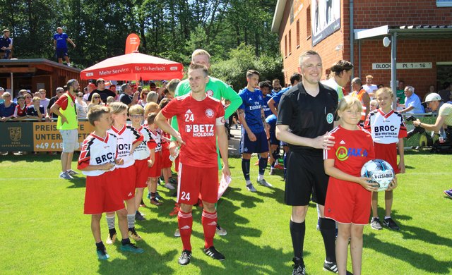 Schiri Sascha Thielert mit den beiden Teams und den Buchholzer Einlaufkindern