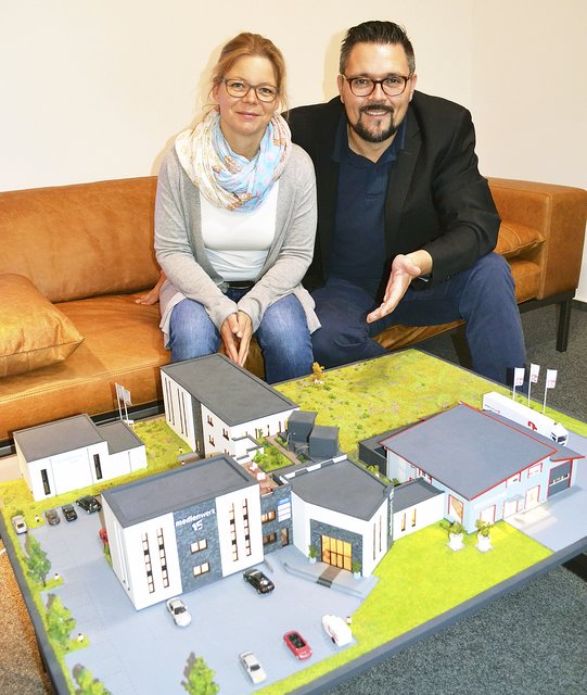 Alexandra und Klaas Dittmer mit dem Modell, das all ihre Unternehmen im Maßstab 1:45 abbildet: vorne rechts das Druckstudio, links daneben das Medienwerk 15 und schräg rechts dahinter der Medienwerk-Anbau