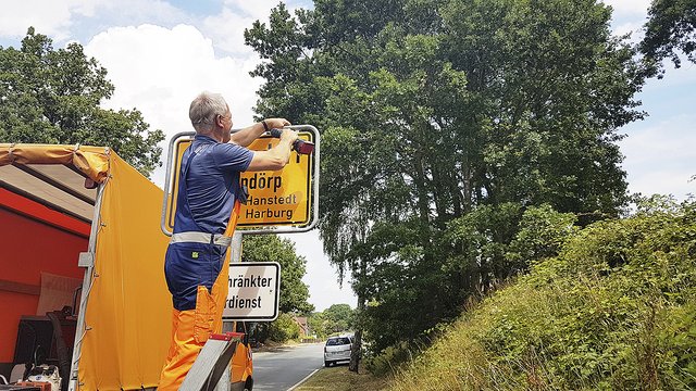 Ein Mitarbeiter des Bauhofs tauscht die erste Ortstafel aus