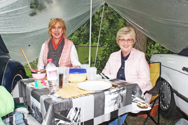 Sylvia (li.) und Britta hatten zwischen ihren Autos eine Plane gegen den Regen gespannt, unter der sie campten