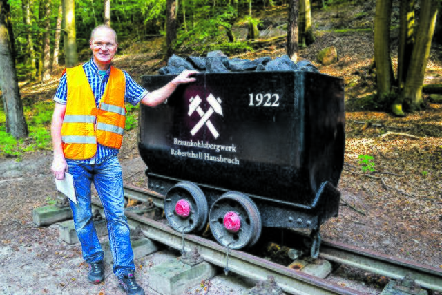 Rolf Weiß mit dem Bergwerksdenkmal, einer Lore
