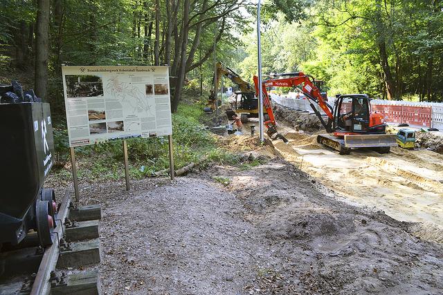 Links die Lore als Bergwerksdenkmal und die Informationen zum früheren Braunkohleabbau, 
rechts die Baufahrzeuge