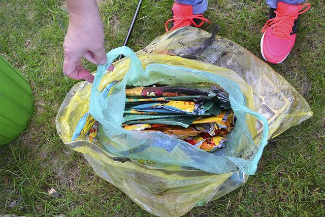 Eine ganze Tüte voll mit ordentlich zusammengefaltetem Plastikmüll, der wild in der Landschaft entsorgt wurde