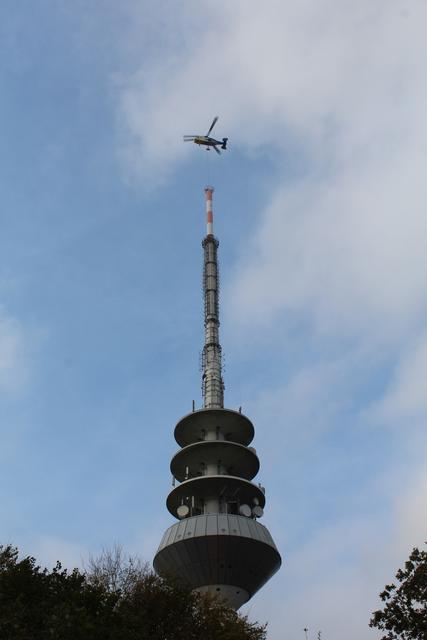 Der obere Teil der Spitze wird von Arbeitern im Inneren des Turms am Hubschrauber befestigt