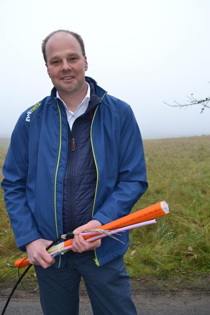 Björn Muth, EWE-Kommunalbetreuer der Geschäftsregion Bremervörde/Seevetal, mit dem Leerrohr (orange) und Glasfaserkabeln