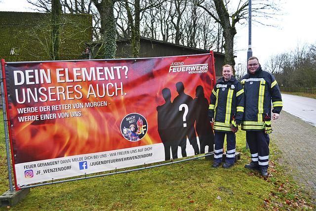 Freuen sich auf neue Kinder- und Jugendfeuerwehrmitglieder: die Jugendwarte Angelina Kloss und Patrick Rachold neben einem der Banner, mit dem um Nachwuchskräfte geworben wird