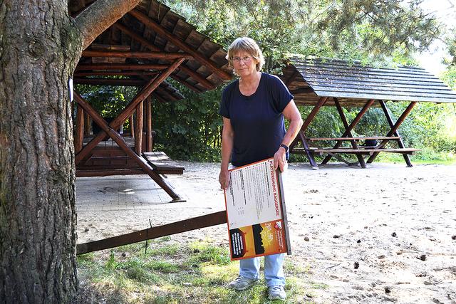 TSV-Vorsitzende Renate Preuß mit einem mutwillig
herausgerissenen Schild am Grillplatz auf dem
Baggerseegelände des Todtglüsinger Sportvereins