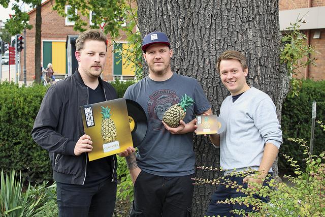 Präsentieren das neue "Drei Meter Feldweg"-Album (v. li.): Hendrik Petersen mit der Vinyl-Scheibe, Bennet Ramm mit der Cover-Ananas und Philip Hellmig mit der CD-Version