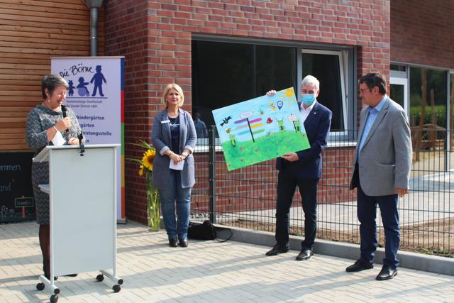 Stefanie Mencke (li.), Geschäftsführerin der Börne, und Kindergartenleiterin Sonja Elbert überreichen Bürgermeister Harald Koetzing (2.v.re.) und Samtgemeinde-Bürgemeister Rainer Schlichtmann ein Bild, das die Kindergartenkinder gemalt haben