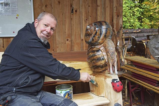 Künstler Eric Peter ölt das Holz seiner Sitzbank, die er mit Schnecke "Karo" verziert hat  | Foto: ts