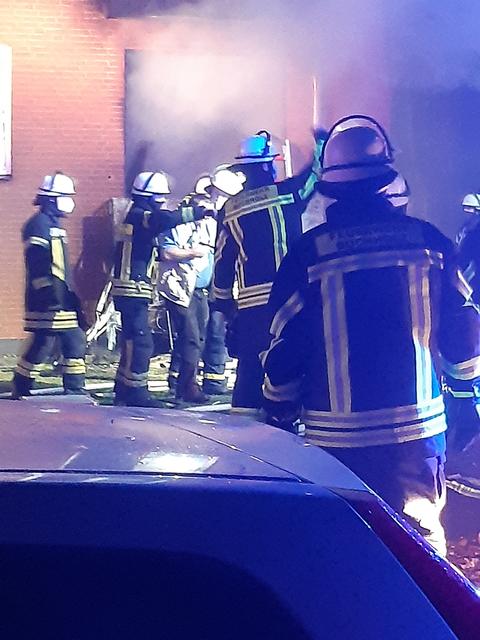 Feuerwehrkräfte begleiten einen Bewohner aus dem verqualmten Haus