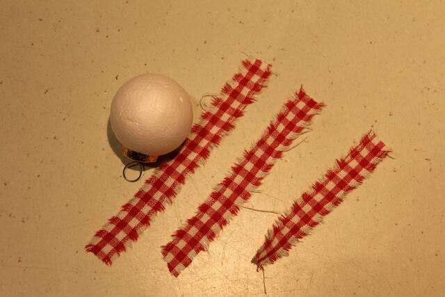 Für die Christbaumkugel benötigt man Styroporkugeln, Stoffreste, Stoffband, Christbaumkugelanhänger (z.B. von kaputten Kugeln), Kleber, Schere