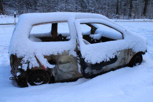 Ausgebranntes Wrack mit Schnee innen und außen auf dem Parkplatz am Sunder