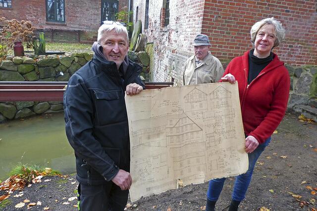 Mühlenbauer Olaf Rieck (v. li.), Müllermeister Franz Rosenkranz und die Mühlenvereinsvorsitzende Emily Weede zeigen den detailreichen Bau- und Konstruktionsplan der Wassermühle Karoxbostel