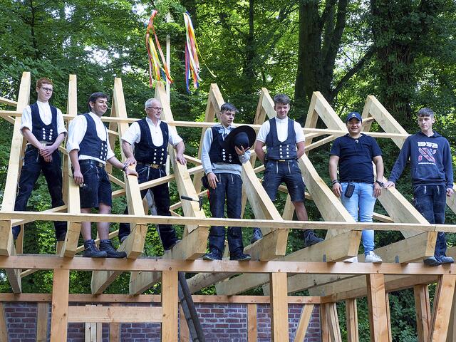 Angehende Zimmerleute und ihre Ausbilder von den Berufsbildenden Schulen Buchholz beim Richtspruch auf dem Dach des Schmiedebaus in Karoxbostel