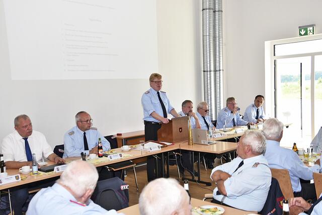 Gemeindebrandmeister Jörn Petersen (am Pult) und Kreisbrandmeister Volker Bellmann (li. daneben) beim Treffen der Alterskameraden