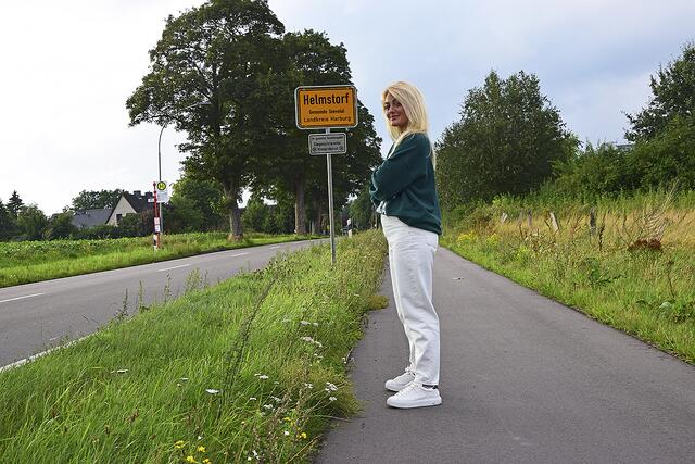 "Aus diesem Dorf komm ich": Schauspielerin Anuschka van Lent steht lässig zum Foto am Ortschild des Seevetaler Ortsteils Helmstorf | Foto: ts