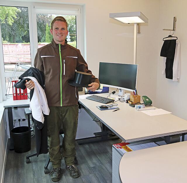 Der neue Friedhofsleiter in seinem Büro. Er trägt sein normales Arbeits-Outfit. Frack und Zylinder sind für die Beerdigungen immer griffbereit