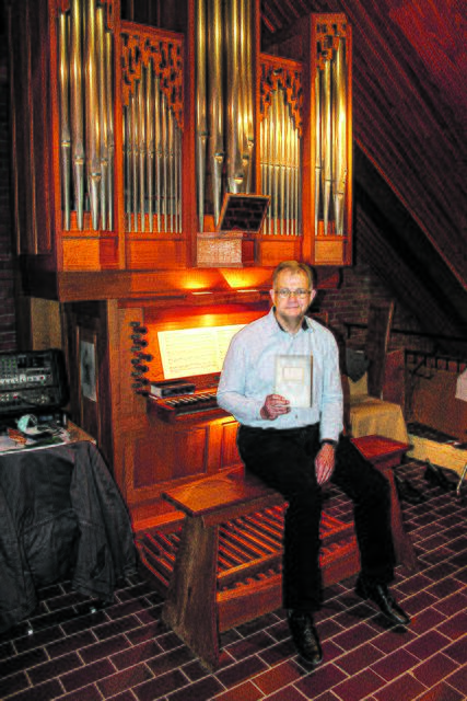Jürgen Pohl vor der Orgel in der Klecker Thomaskirche, in seiner Hand das von ihm gefundene Buch