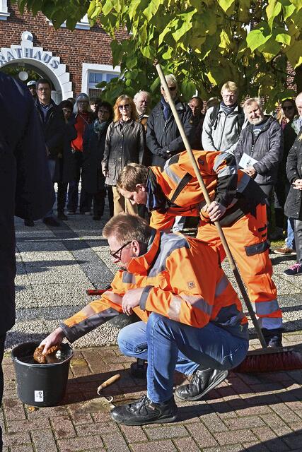 Frank Hoppe vom Fachbereich Bauen der Samtgemeinde Tostedt (vorn) reinigt den Stolperstein nach der Verlegung | Foto: bim
