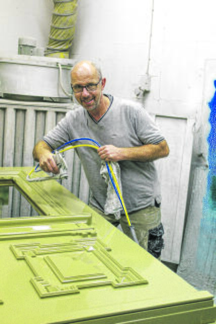 Tischler- und Kreishandwerksmeister Bernd Hintze veredelt mit einer Lackierpistole eine neue, auf alt getrimmte Haustür nach den Anforderungen des Denkmalschutzes | Foto: ce
