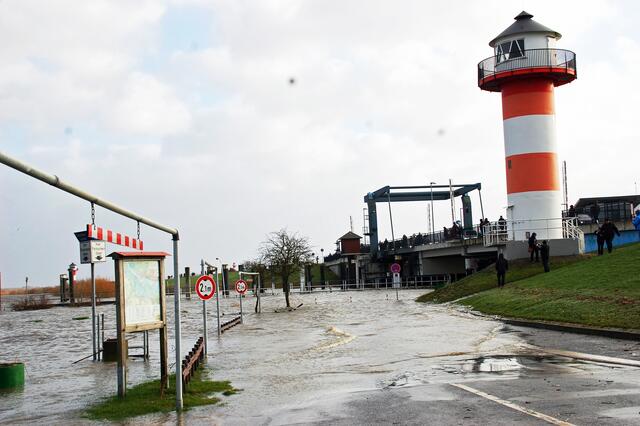 Das Wasser läuft gegen den Deich, auf dem etliche Schaulustige die Flut beobachten