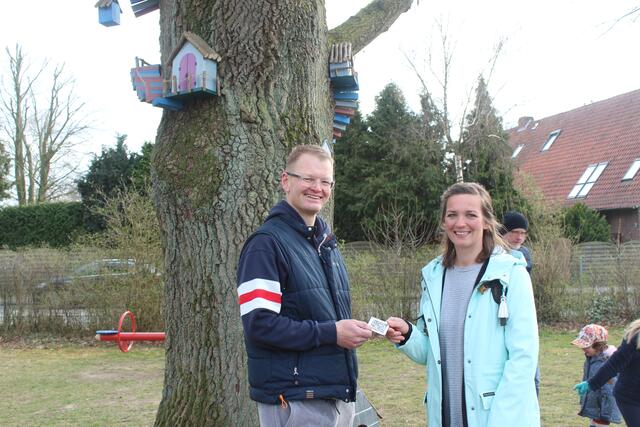 Ole Petersen vom SV Beckdorf übergibt Martha Erdmann von der Spielplatzinitiative den QR-Code 