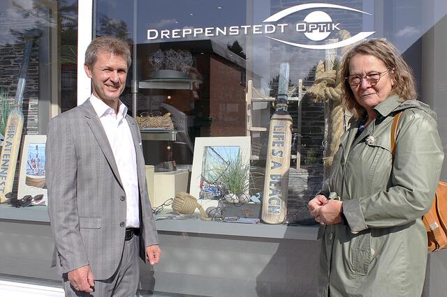 Holger Wiese, Inhaber von Dreppenstedt-Optik, mit Ingrid Zirpins und ihren Gemälden vor seinem Schaufenster | Foto: Marion Wenner