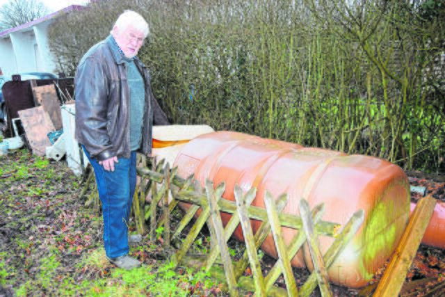 Claus Neugebauer an einem Regenwassertank. Das sei Material, das er noch verwenden können und kein Abfall, sagt er | Foto: ts