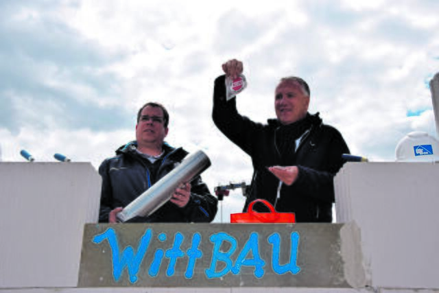 Bauherr Jörg Schröder (re.) legt einen Aufkleber der Bürgerinitiative Trassenalarm in die Zeitkapsel. Neben ihm hält Bauleiter Jens Böttcher die wasserdichte Dokumentenrolle. | Foto: ts