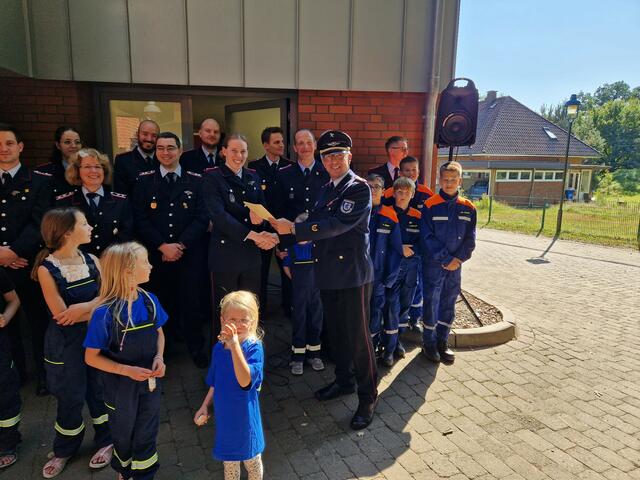 Kreisbrandmeister Volker Bellmann übergibt die Urkunde zum Geburtstag an Jugendfeuerwehrwartin Lina Matthies | Foto: Samtgemeinde Jesteburg