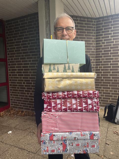 Frank Patyna, Schulleiter des Gymnasiums Hittfeld, hilft beim verstauen der Geschenke im Wagen der Tafel | Foto: sra