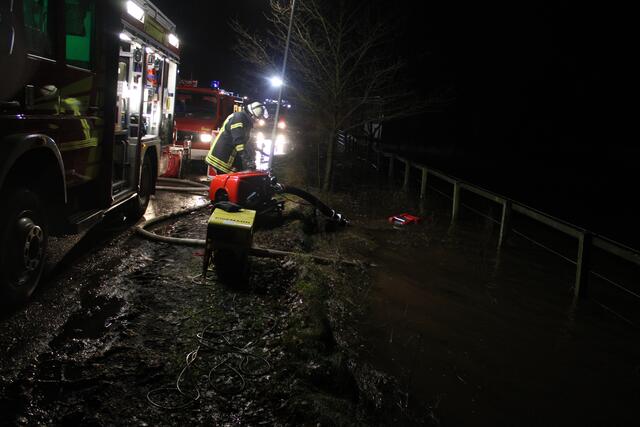 Feuerwehrleute pumpen das Wasser von einer überfluteten Wiese neben der Straße | Foto: ce
