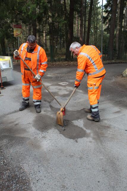 "Team Asphalt" Guido Kleen (li.) und Marcel Andres demonstrieren, wie ein Schlagloch auf einer asphaltierten Straße mit Kaltasphalt repariert wird | Foto: pm