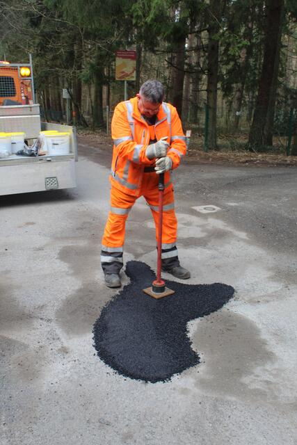 Guido Kleen demonstriert, wie ein Schlagloch auf einer asphaltierten Straße mit Kaltasphalt repariert wird | Foto: pm