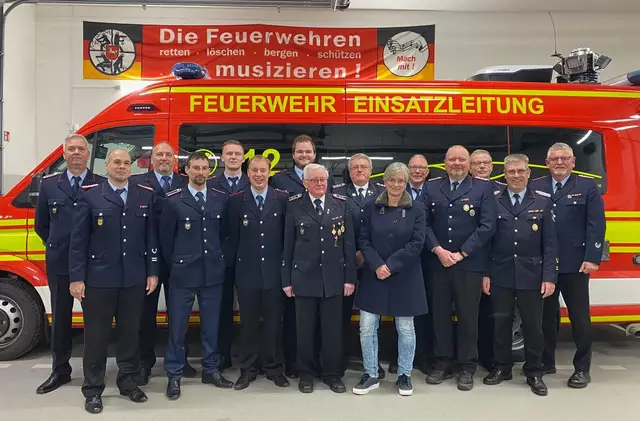 Auf der Versammlung: Samtgemeinde-Bürgermeisterin Kathrin Bockey mit dem geehrten Spielmannszug-Mitbegründer Helmut Wiegels (li. neben ihr) sowie beförderten Feuerwehrleuten und Gratulanten | Foto: Janine Richter