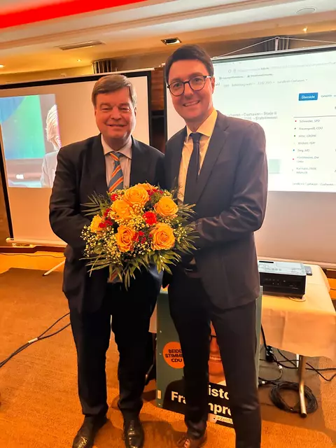Gratulation zum Wahlsieg: Enak Ferlemann (CDU, li.), der den Wahlkreis Cuxhaven - Stade II 2021 an Daniel Schneider von der SPD verloren hat, überreicht seinem Parteifreund Christoph Frauenpreiß einen Blumenstrauß. Frauenpreiß hat den Wahlkreis für die CDU zurückerobert