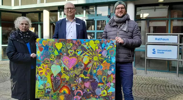 Stefanie Andreas und Ruben Pampoukidis, Veranstalter der Demonstration in Stade, übergeben Bürgermeister Sönke Hartlef (Mitte) das bunte Kunstwerk | Foto: Hansestadt Stade