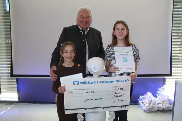 Heiner Schönecke mit Mara Tabea Warrelmann (re.) und Isabell Özdemir, die im Namen des Gymnasiums Meckelfeld den Scheck für den ersten Platz entgegennahmen. Roboter Pepper zeigte sich ein wenig kamerascheu | Foto: pm