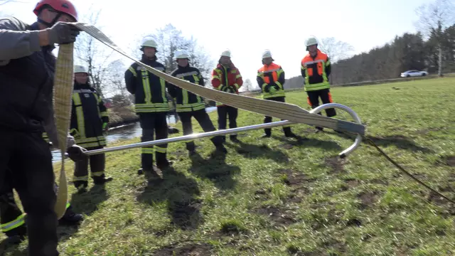 Mit Hirtenstab und Fädelstange ziehen die Teilnehmer den Breitgurt unter dem Pferd durch | Foto: Feuerwehr Moor