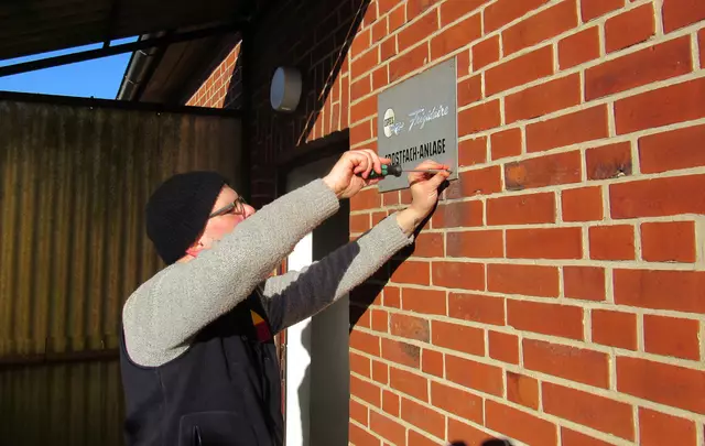 Museumsmitarbeiter Alexander Kollecker schraubt das Schild des Kalthauses in Lindhorst ab, auch das geht ins Museum