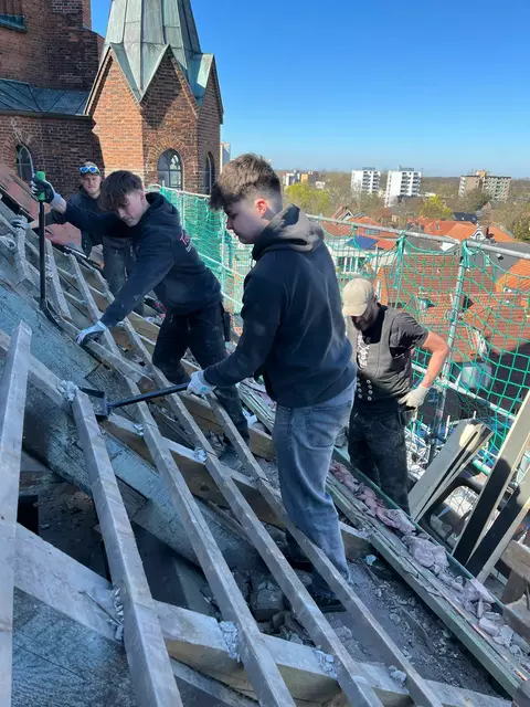 Gesellen, ein Azubi und ein Schülerpraktikant bei der Arbeit auf dem Kirchendach | Foto: Tobias Holst